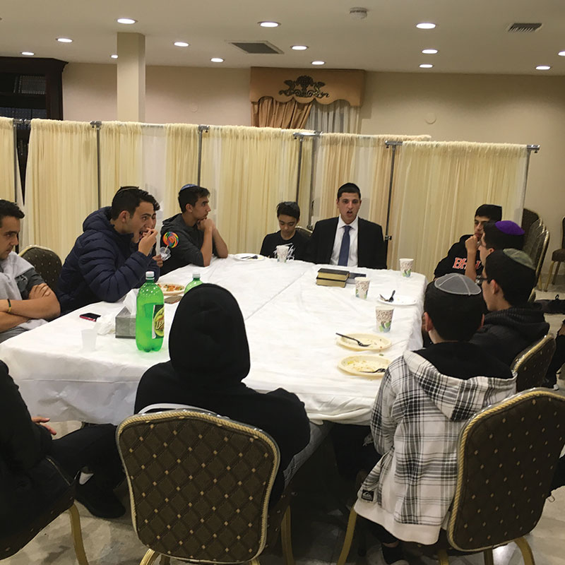 Young men around the table after davening at Bait Aaron